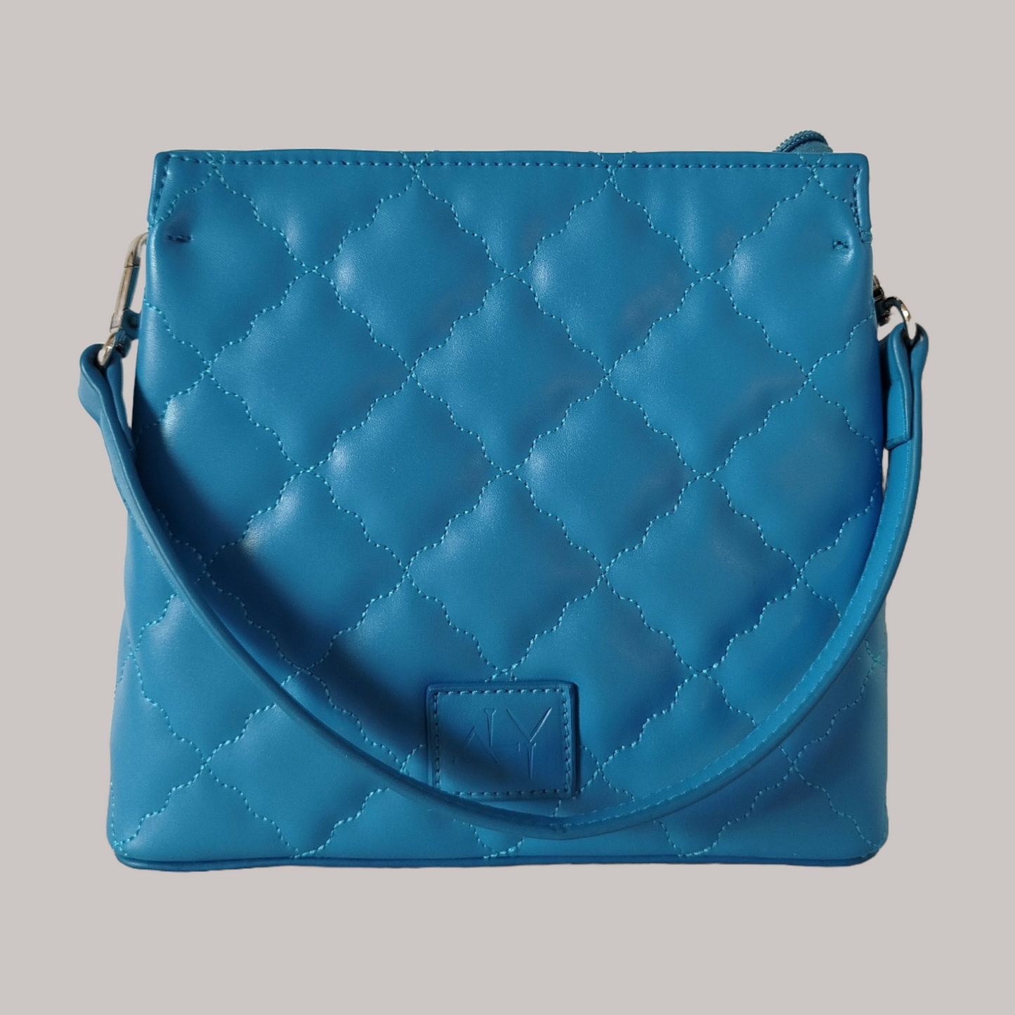 Blue quilted handbag with a wavy diamond stitch design and single handle 